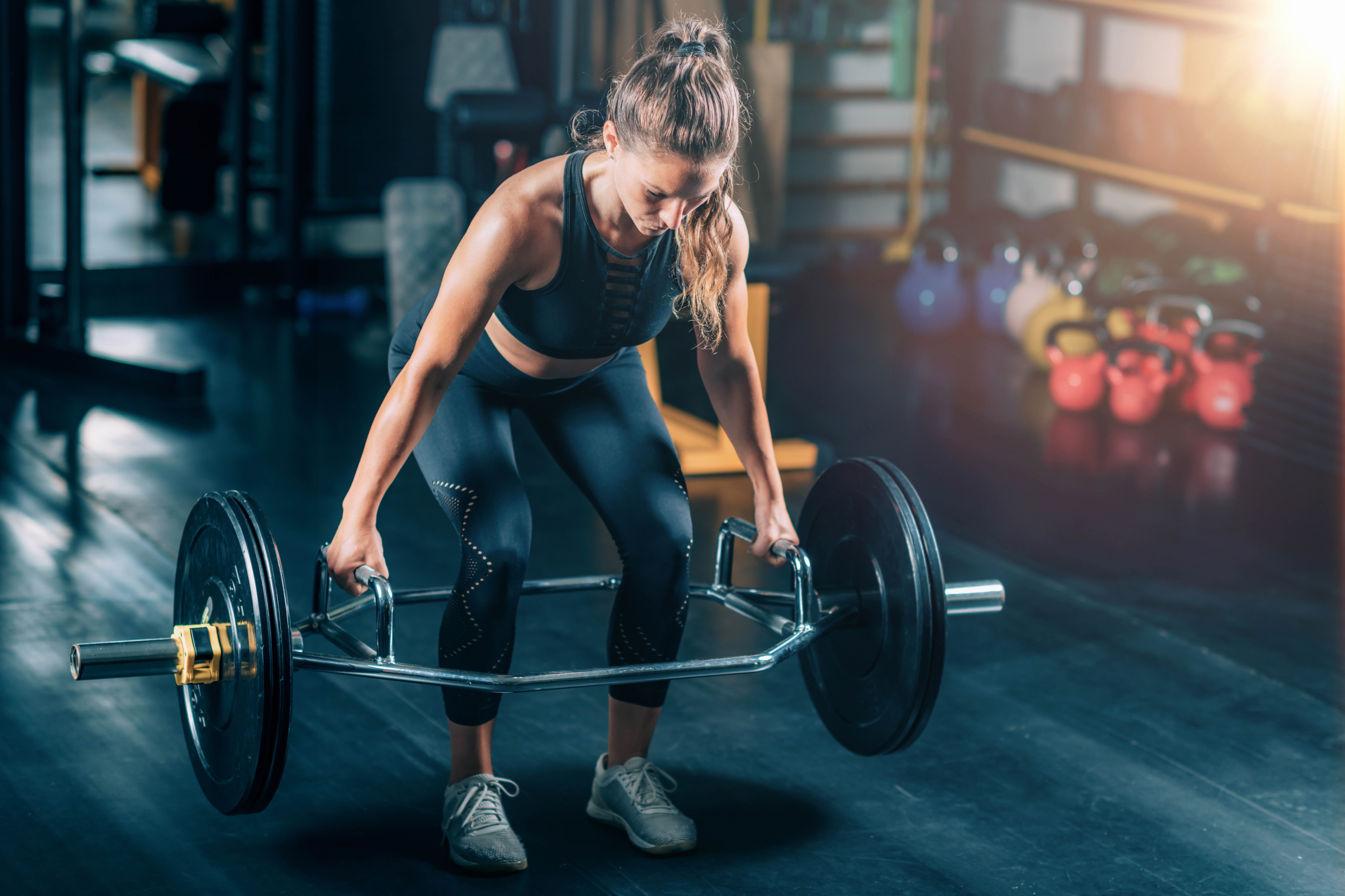Strong woman lifting a trap bar deadlift in a gym Strong woman lifting a trap bar deadlift in a gym